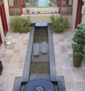 granite water feature lined with river cobble, basalt patio